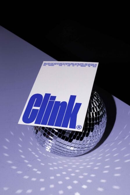 Disco ball reflecting light with a bold blue Clink postcard overlay, ideal for graphic designers. Perfect mockup for branding and typography projects.