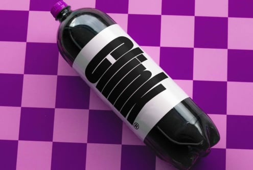 Soda bottle mockup with bold black typography on white label against a purple checkered background perfect for graphic design branding templates.