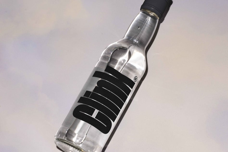 Spirit bottle wrapped with black textured label band on subtle pastel sky background