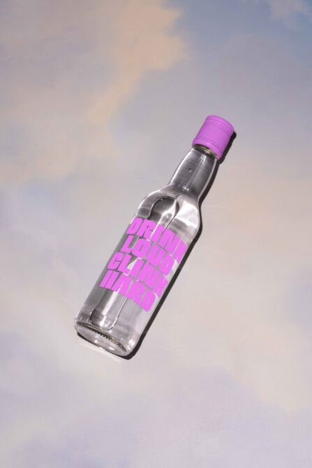 Bottle with bright magenta cap displaying pink Olink lettering on cloudy sky backdrop