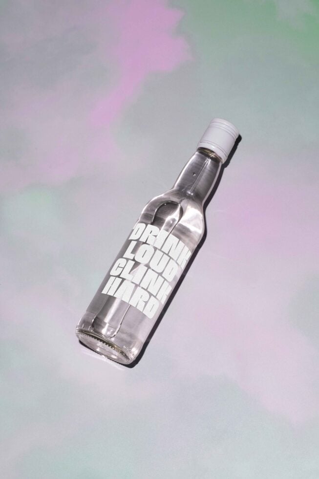 Clear glass bottle with bold typography design lying on a pastel background ideal for mockup or template use graphic design asset packaging label
