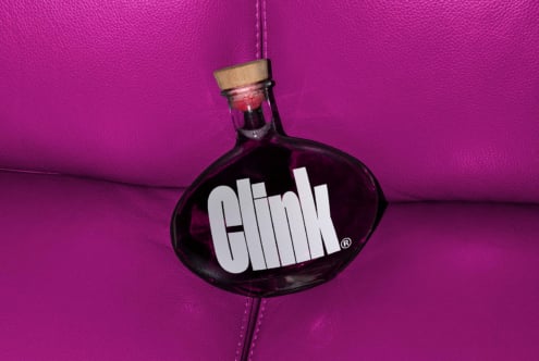 Glass bottle with cork stopper on vibrant pink leather surface featuring bold Clink typography Modern mockup design digital assets for designers SEO