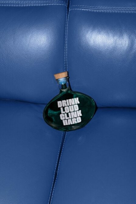 Green teardrop bottle hanging against bright blue leather background