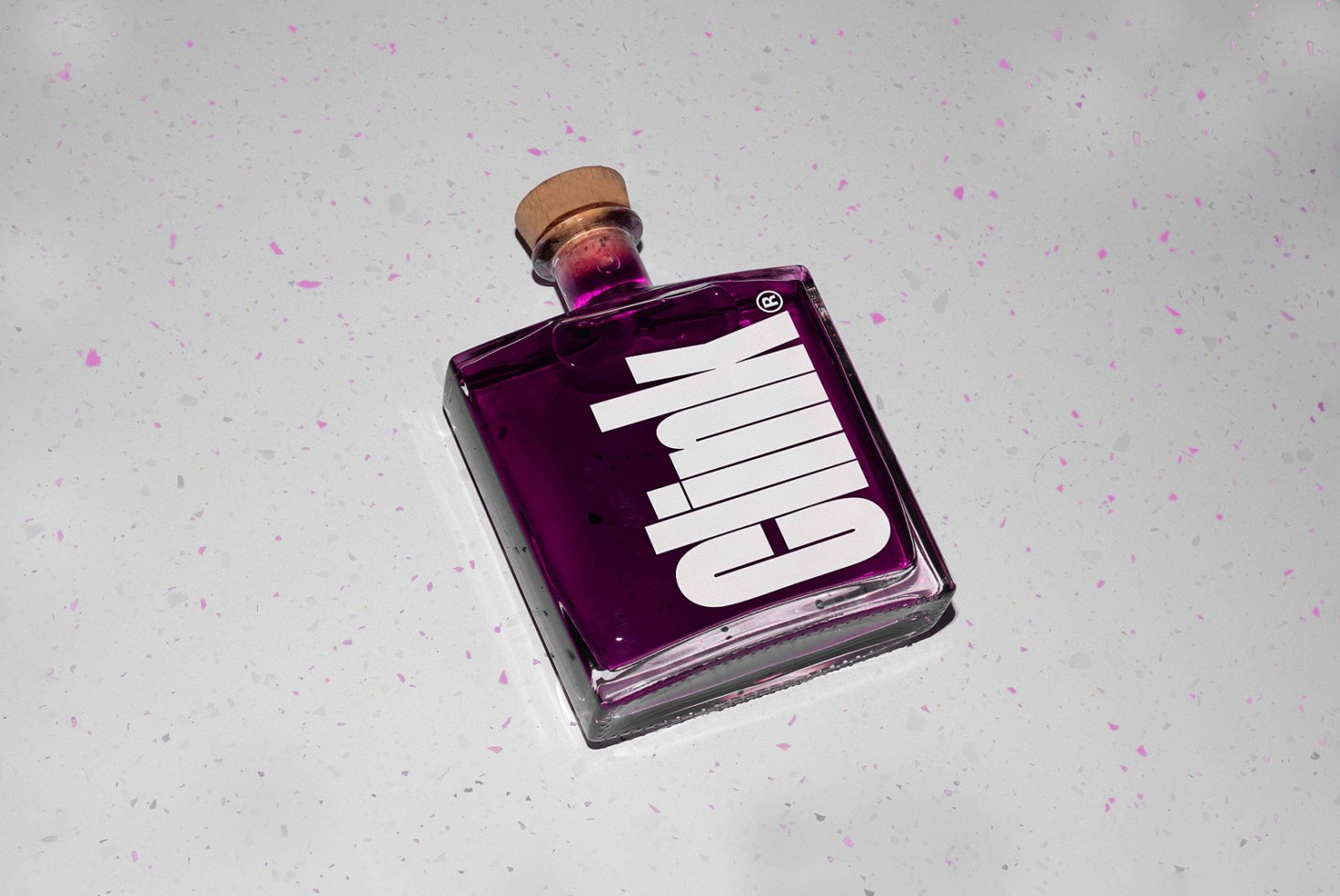 Purple liquid in a square glass bottle with a cork on a speckled gray surface. Suitable for graphic design mockups and product display templates.