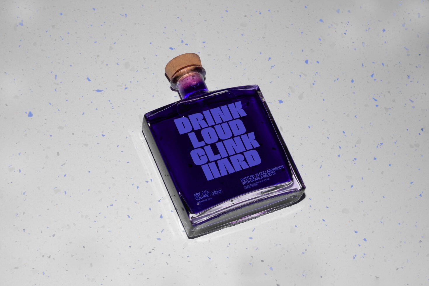 Purple bottle with the words Drink Loud Clink Hard on speckled gray background. Suitable for mockup, packaging design, and branding projects.