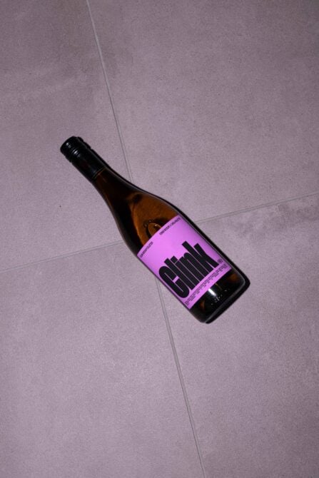Wine bottle on tiled floor with purple label and bold typography perfect for branding mockups packaging design templates and graphic design projects.