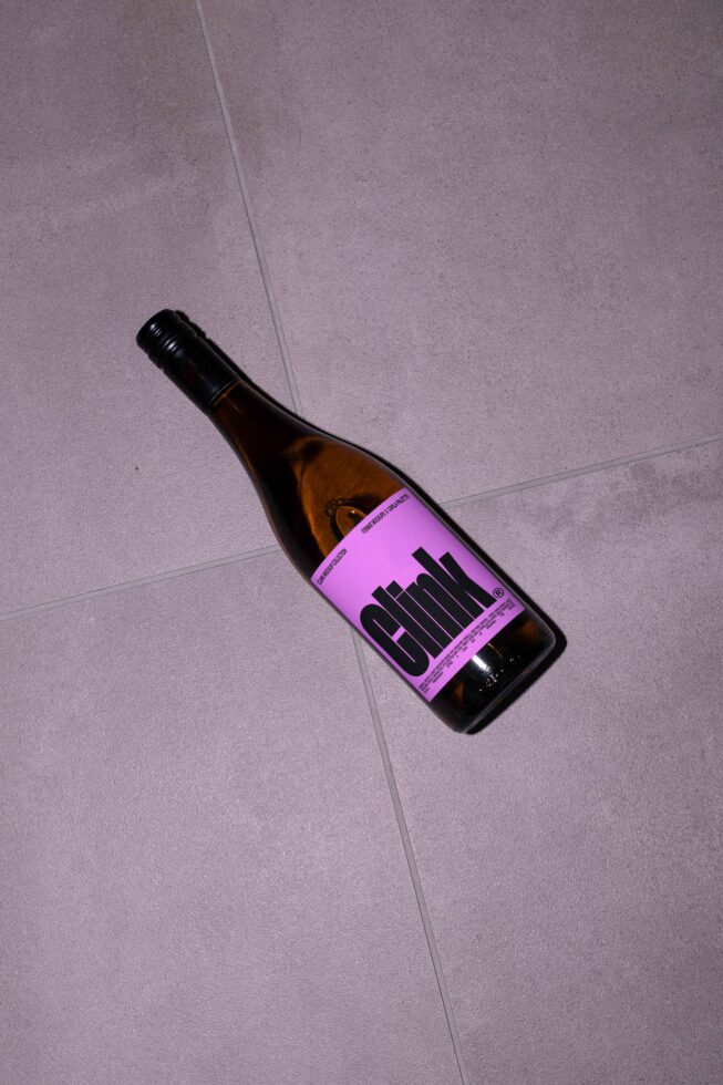 Wine bottle on tiled floor with purple label and bold typography perfect for branding mockups packaging design templates and graphic design projects.