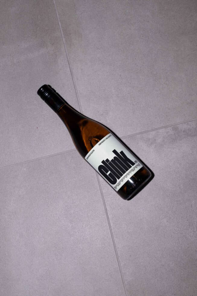 Amber wine bottle on gray tile floor with bold typography. Perfect for designers seeking unique label graphics. Ideal for branding mockups.