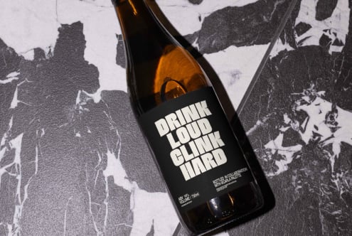 Brown glass bottle on black and white marble, label showing bold sans-serif font. Ideal for product mockups, branding, packaging design templates.