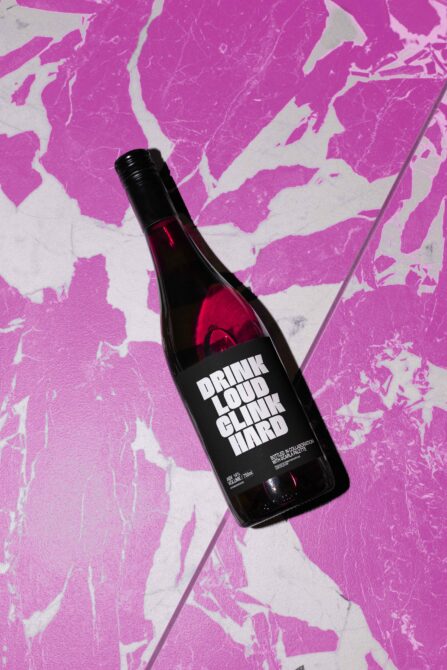Red wine bottle with black label on hot pink marble texture