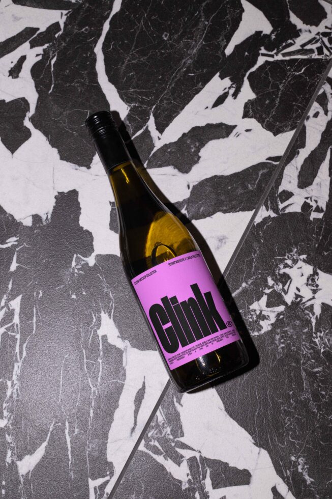 Wine bottle with a pink label on a black and white marble surface, perfect for mockup design and product branding presentations. Keywords: mockup, design.