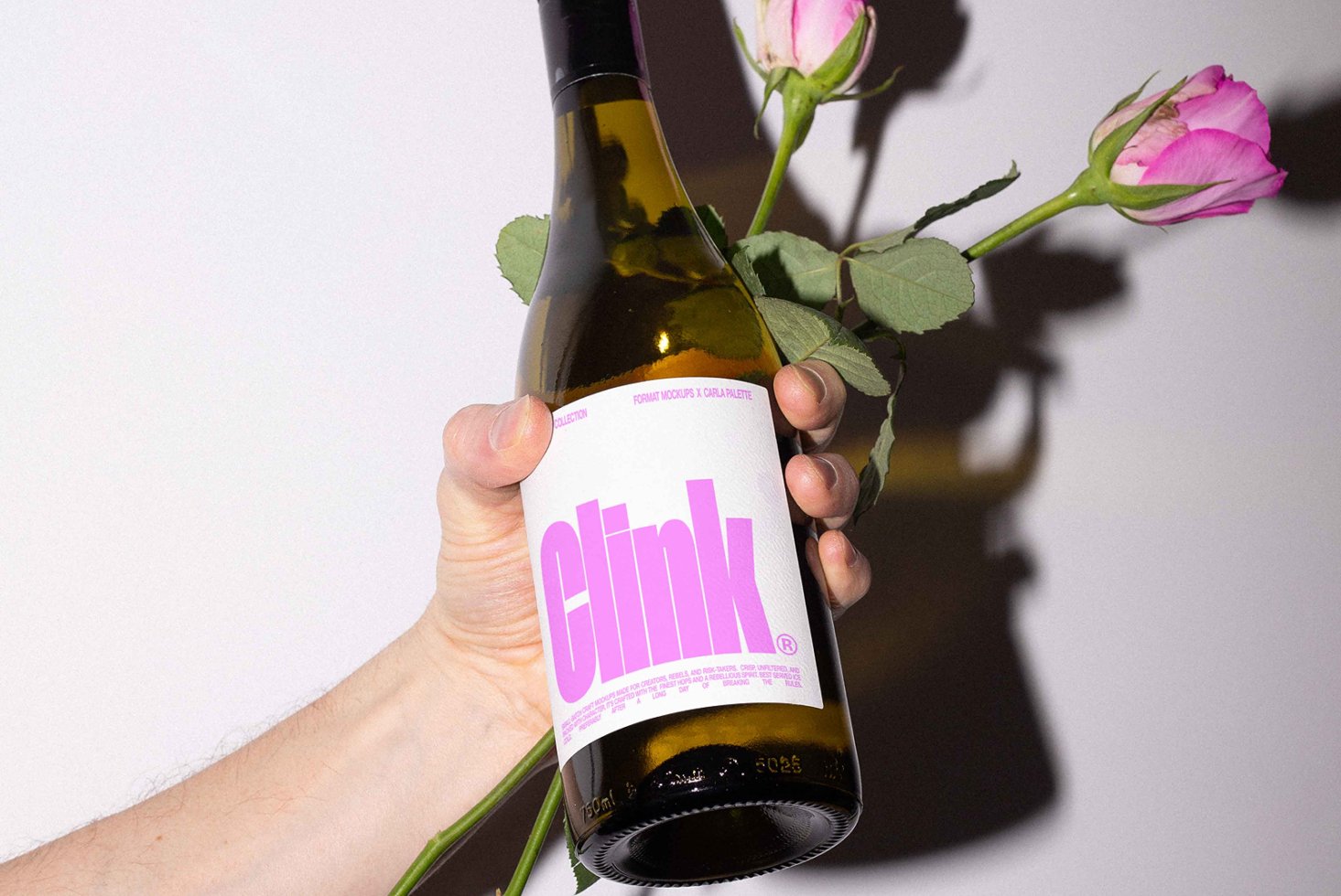 Hand holding wine bottle with bold pink label and pink roses. Ideal for mockup designs, showcasing packaging, floral themed projects.