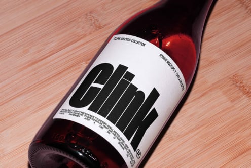 Bottle mockup on wooden surface features bold black typography label. Perfect for designers seeking premium packaging templates.