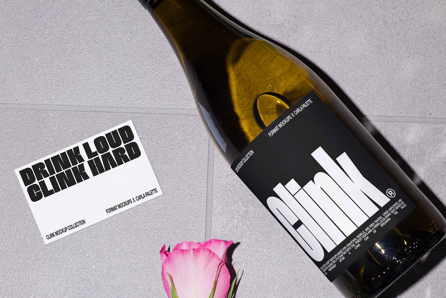 Wine bottle mockup on a tiled surface with a pink rose and a card reading Drink Loud Clink Hard. Perfect for product branding and graphic design.