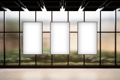 Three vertical poster mockups in a modern interior with large windows and blurred outdoor view ideal for graphic design and branding presentations