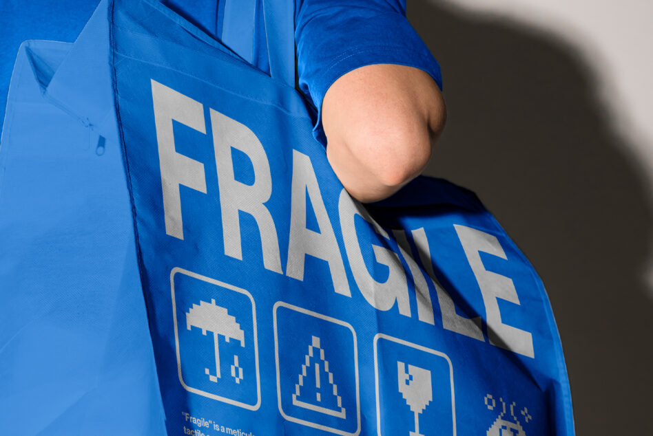 Blue windbreaker close up showing FRAGILE text with person's shoulder visible