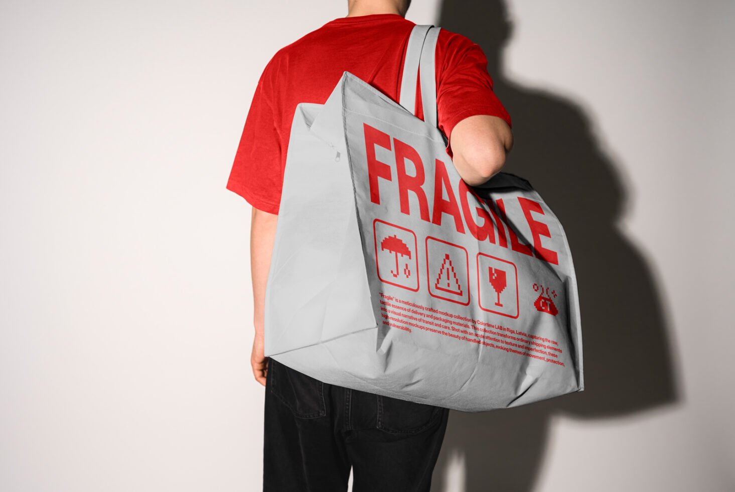 Mockup of a person carrying a large gray tote bag with red Fragile text and icons, ideal for packaging design and marketing concepts in graphic design.