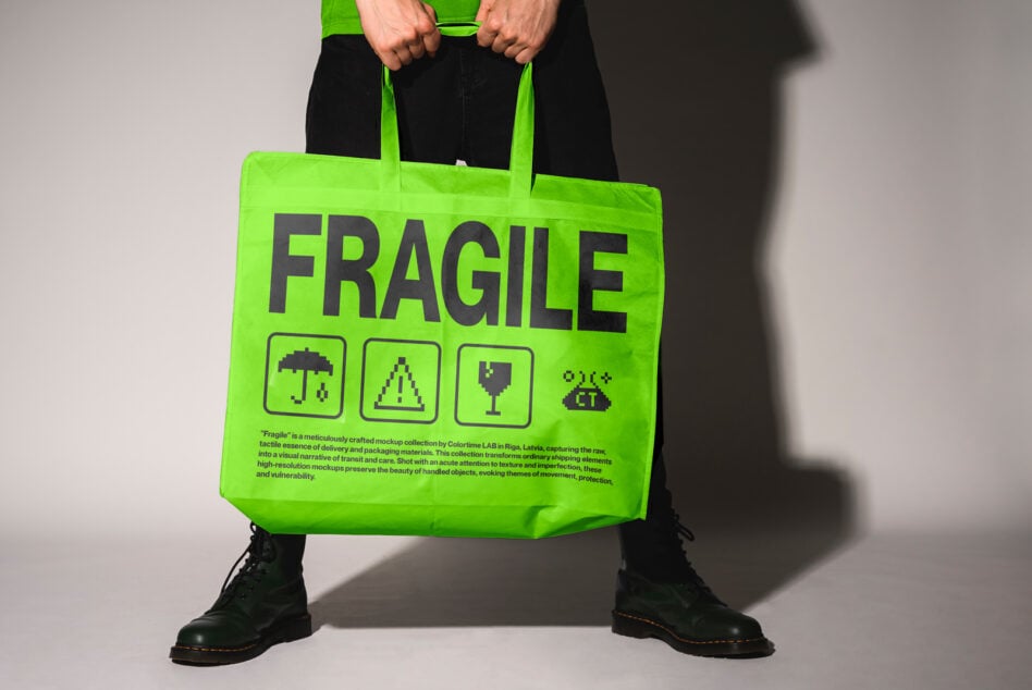 Neon green tote bag with FRAGILE text, pixel icons, held by person in black pants