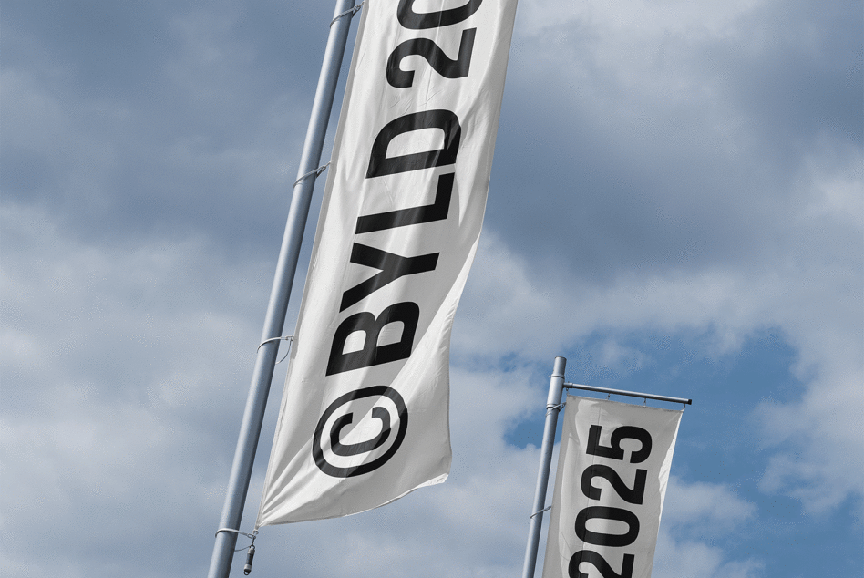 Two vertical flags on poles against a cloudy sky labeled with BYLD 2025. Perfect for graphic and mockup designers needing sky-themed templates and concepts.
