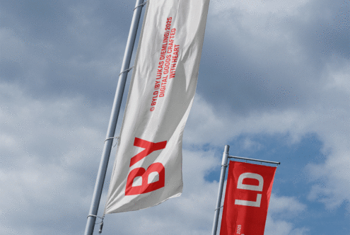 Vertical flags with bold red white text against cloudy sky background ideal for mockup design branding template outdoor advertisement banners.