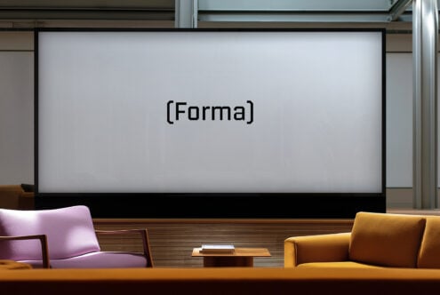 Modern office space with large screen displaying Forma font mockup. Purple and yellow chairs with wooden table for creative design environment.