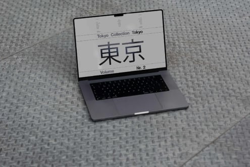 Laptop displaying Tokyo font collection on a metal floor. Ideal for designers seeking unique typography mockups and design templates. High-res graphic asset.