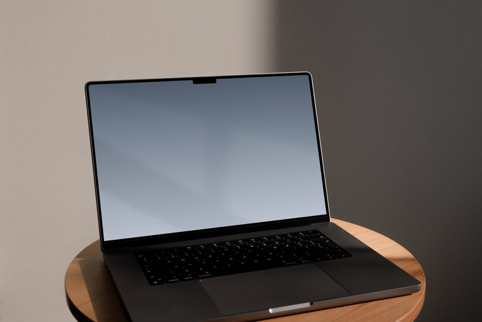 Open laptop on round wood table with blue gradient screen displaying sky