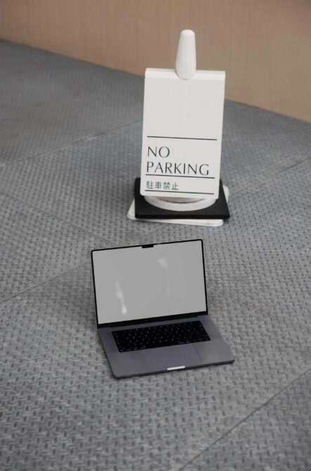 No Parking sign holder with blank laptop screen on textured floor