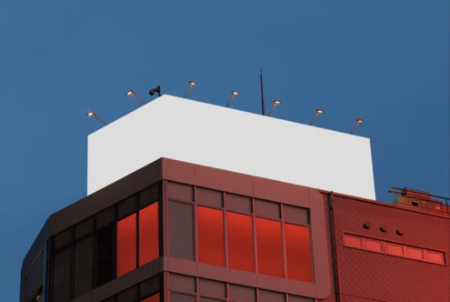 Rooftop billboard mockup on modern building at dusk blue sky background. Ideal for designers creating outdoor advertising templates and graphic displays.