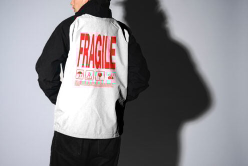Back view of a person wearing a jacket with bold red text Fragile with icons. Apparel design mockup suitable for digital designers and fashion templates.