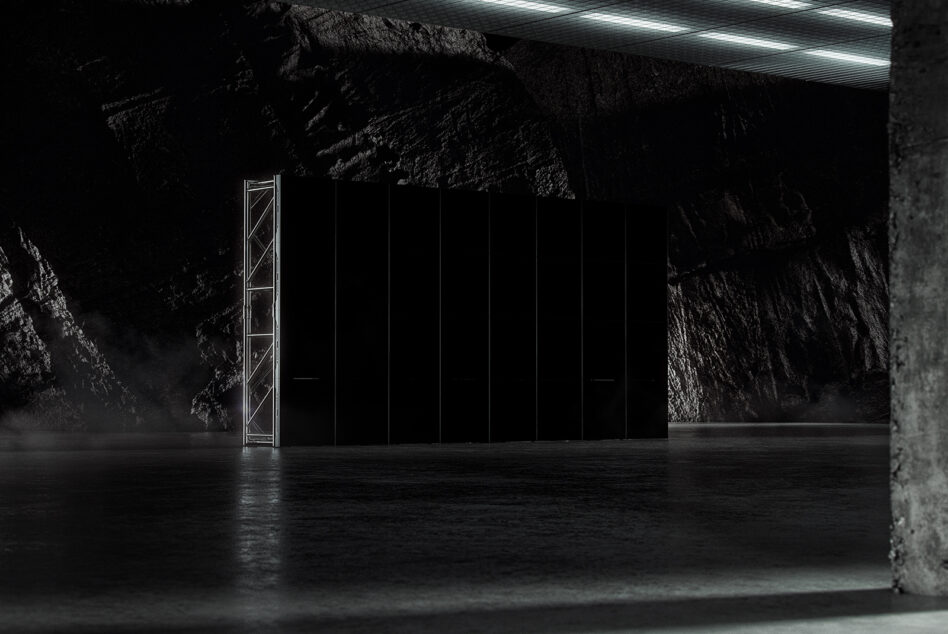 Dark industrial interior showcasing a minimalist black structure with metal framework and concrete textures. Ideal for mockups and graphic design.