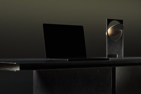 Sleek laptop mockup on modern dark desk with unique metal lamp background contrasting shadows design inspiration technology workspace digital assets