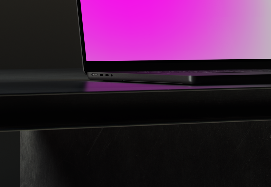 Laptop showing bright magenta gradient display on dark desk