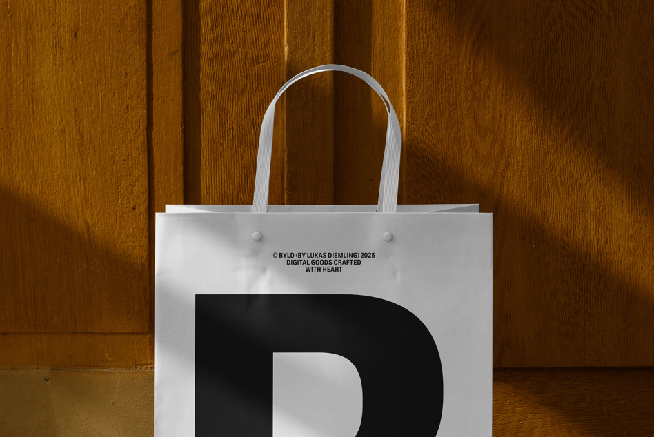 White tote bag with black D letter, white handles against wood paneling