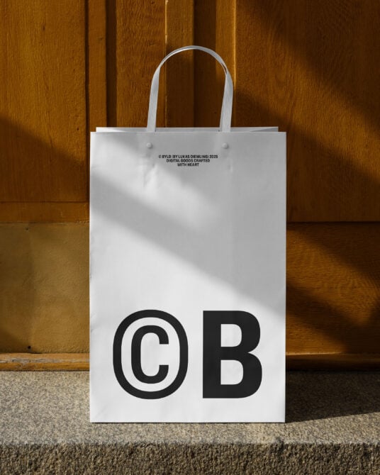 Clean white tote bag on wood floor, outlined copyright B symbol in black
