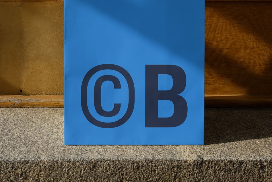 Blue panel with large dark CB letters on concrete ground between textured walls