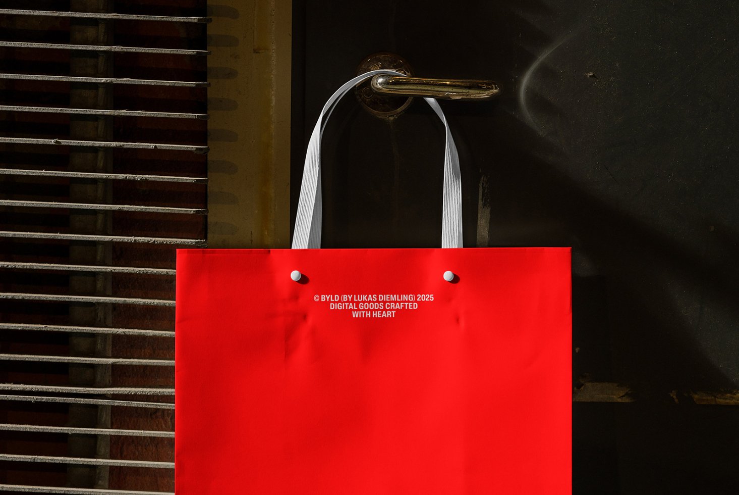 Red tote bag with white handles on metal door handle. Ideal for mockup, template design projects. Enhance branding visuals for designers.