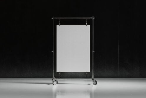 Mockup showcasing a blank poster on a mobile metal stand against a dark background, ideal for design presentations and promotional materials.