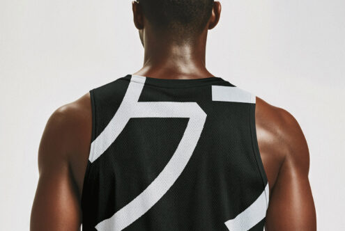 Back view of a person wearing a black mesh sports jersey with bold white graphic elements. Ideal for athletic apparel mockups or graphic design templates.