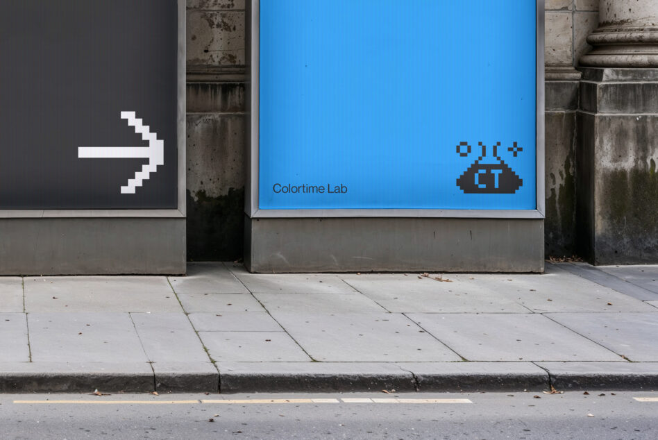 Urban mockup featuring two pixelated digital billboards on a city street corner one black with an arrow the other blue labeled Colortime Lab for designers
