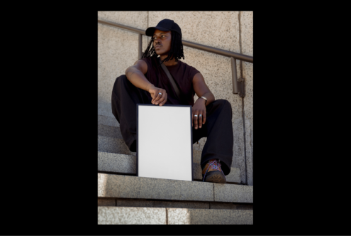 Street style mockup of person sitting on stairs holding blank frame. Urban fashion. Perfect for designers creating poster templates or product displays.
