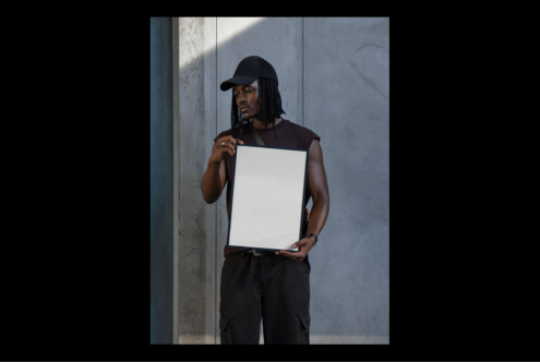 Man holding blank frame mockup in outdoor urban setting. Ideal for showcasing graphic design posters or templates for designers.