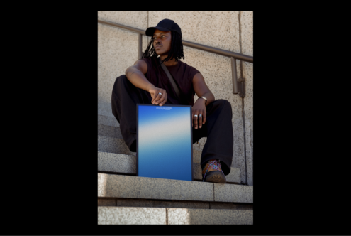 Minimalist poster mockup with gradient blue tones held by person sitting on steps. Ideal for graphics design and templates. Urban setting, stylish vibe.