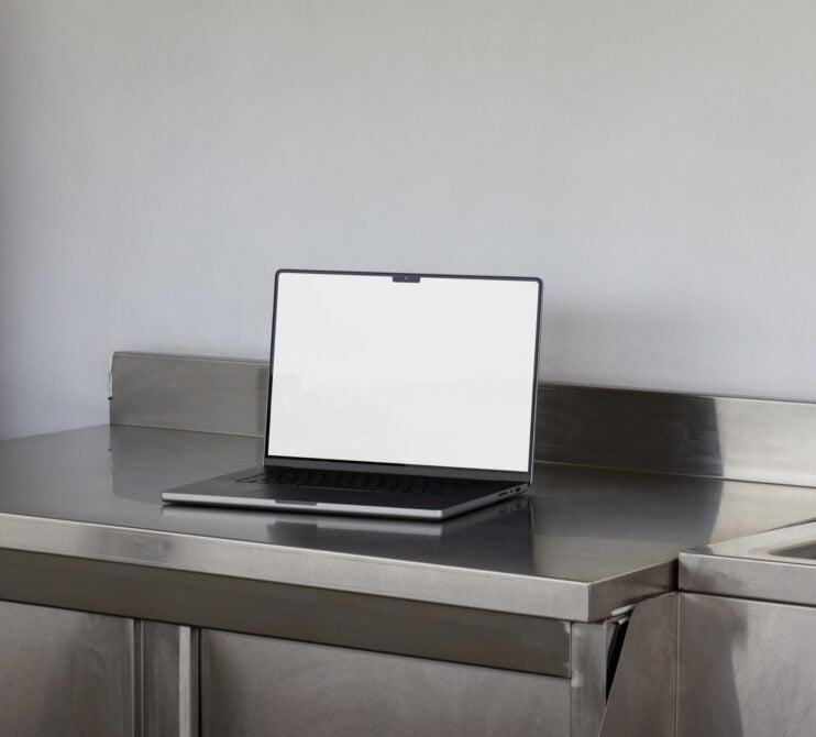 Laptop with blank screen sitting on metal desk between wooden boxes