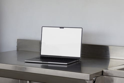 Laptop mockup on a metallic surface perfect for showcasing web designs or graphic templates. Ideal for designers seeking realistic presentation tools.