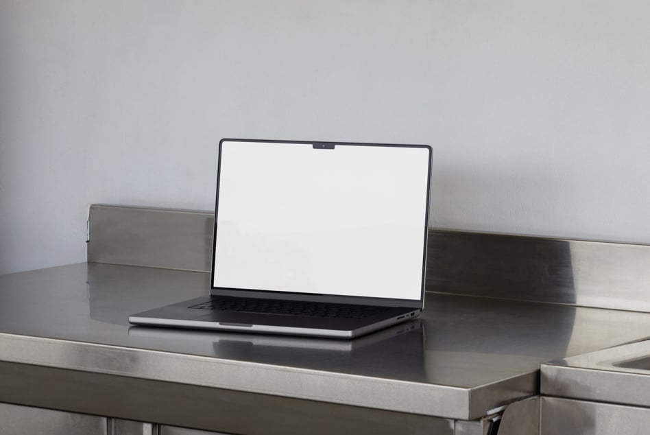 Silver laptop displaying empty white screen on sleek metal table