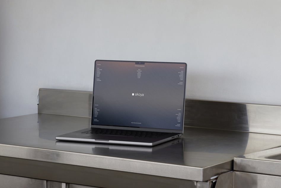 Laptop showing dark interface with akoya branding on metal surface