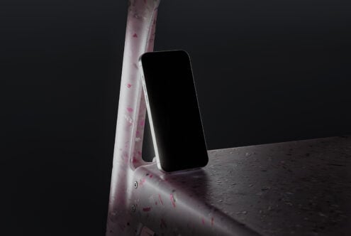 Smartphone leaning on terrazzo pink chair with dark background. Ideal for creating mockups, design presentations, and digital assets. Moody lighting.