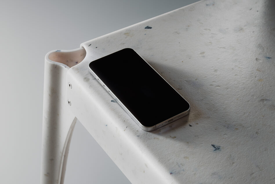 Silver iPhone on white marble shelf with dark screen