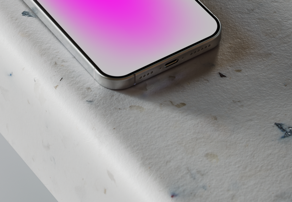 Silver phone angled on textured concrete surface with soft pink gradient on screen